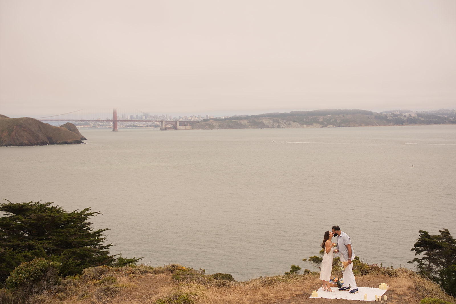 Couple embracing near the Golden Gate Bridge after their proposal