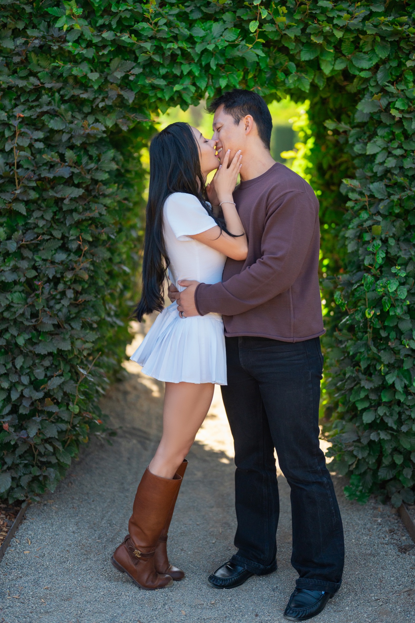 Ernest and Alexandra kissing beneath a leafy arch at Filoli