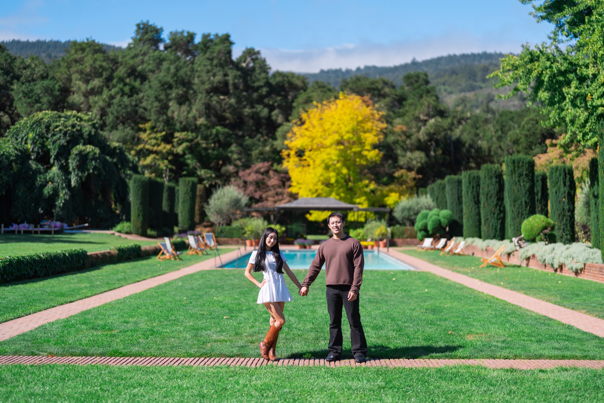 Ernest and Alexandra holding hands beside Filoli’s garden pool with the Santa Cruz Mountains behind them